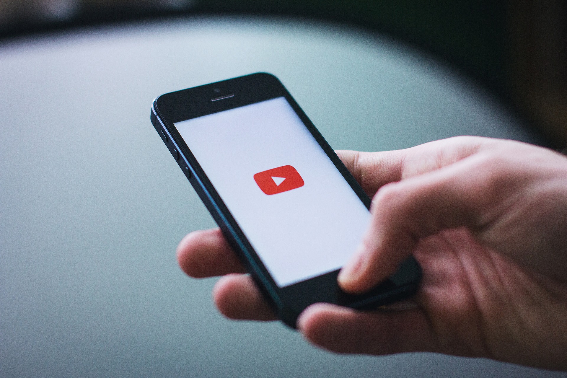 logo Youtube sur l'écran d'un smartphone, placé dans une main