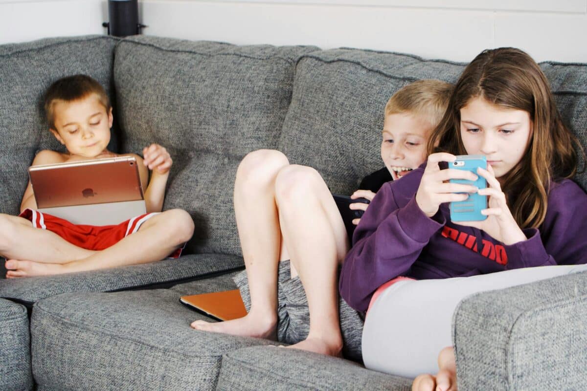 3 enfants sur un canapé devant leurs écrans